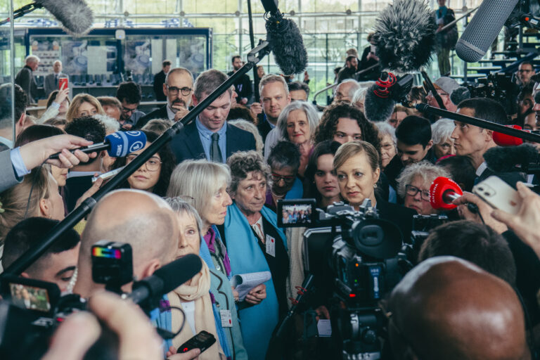 Two swiss activist being surrounded by journalists