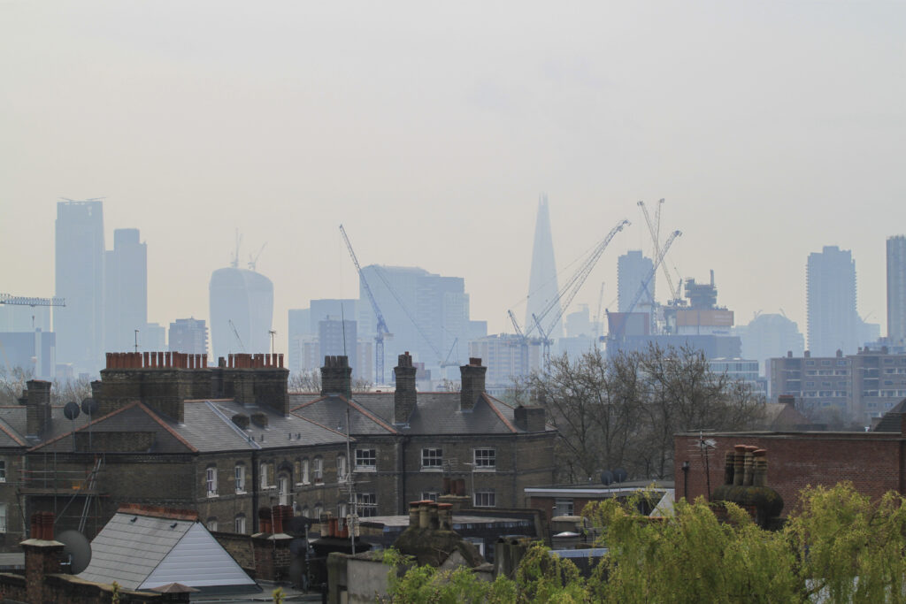 London skyline. Houses in the foreground, central business district in the background. Covered in a hazy smog.