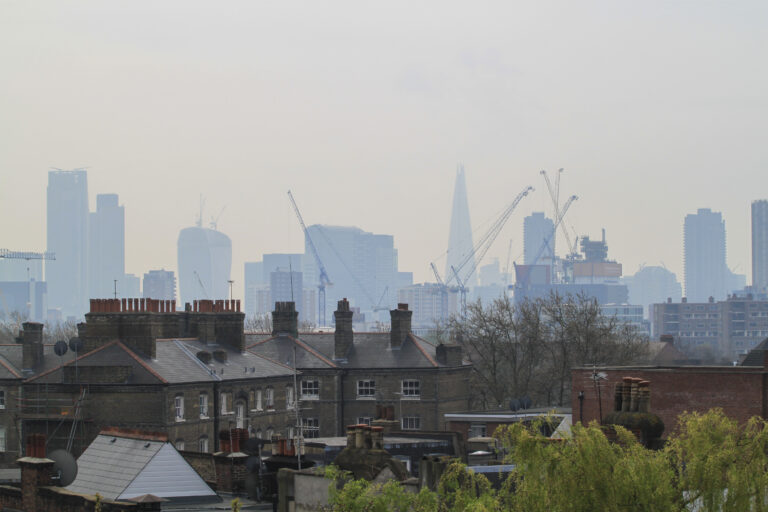 London skyline. Houses in the foreground, central business district in the background. Covered in a hazy smog.