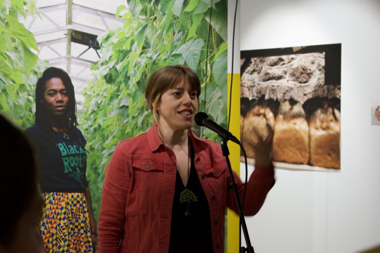 Woman performing spoken word poetry into a mic in a gallery space