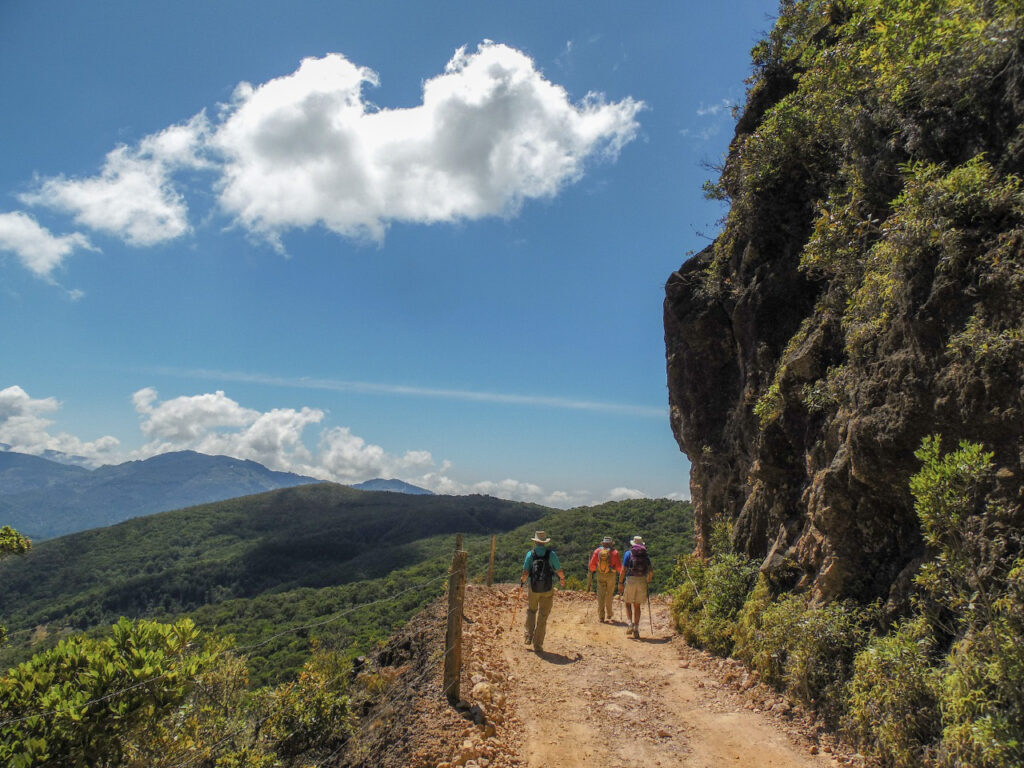 3 hikers on the Camino de Costa Rica trail with blue skies and views on tree covered mountains