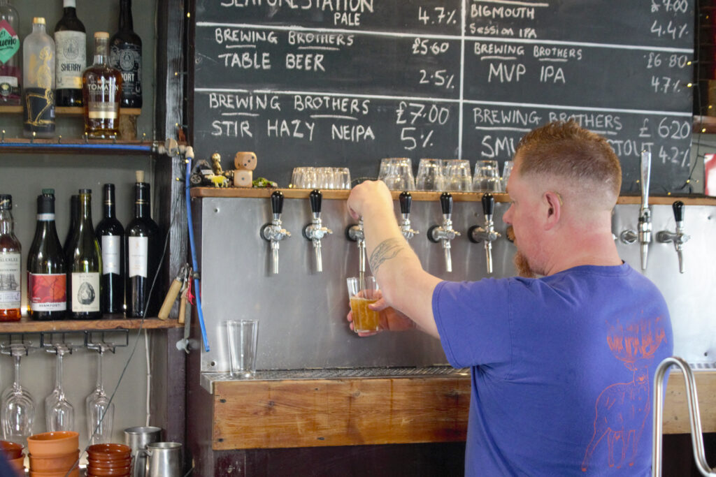 A bartender pulls a pint of the Seaforestation kelp pale ale at The Brewing Brothers