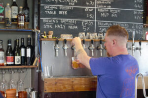 A bartender pulls a pint of the Seaforestation kelp pale ale at The Brewing Brothers