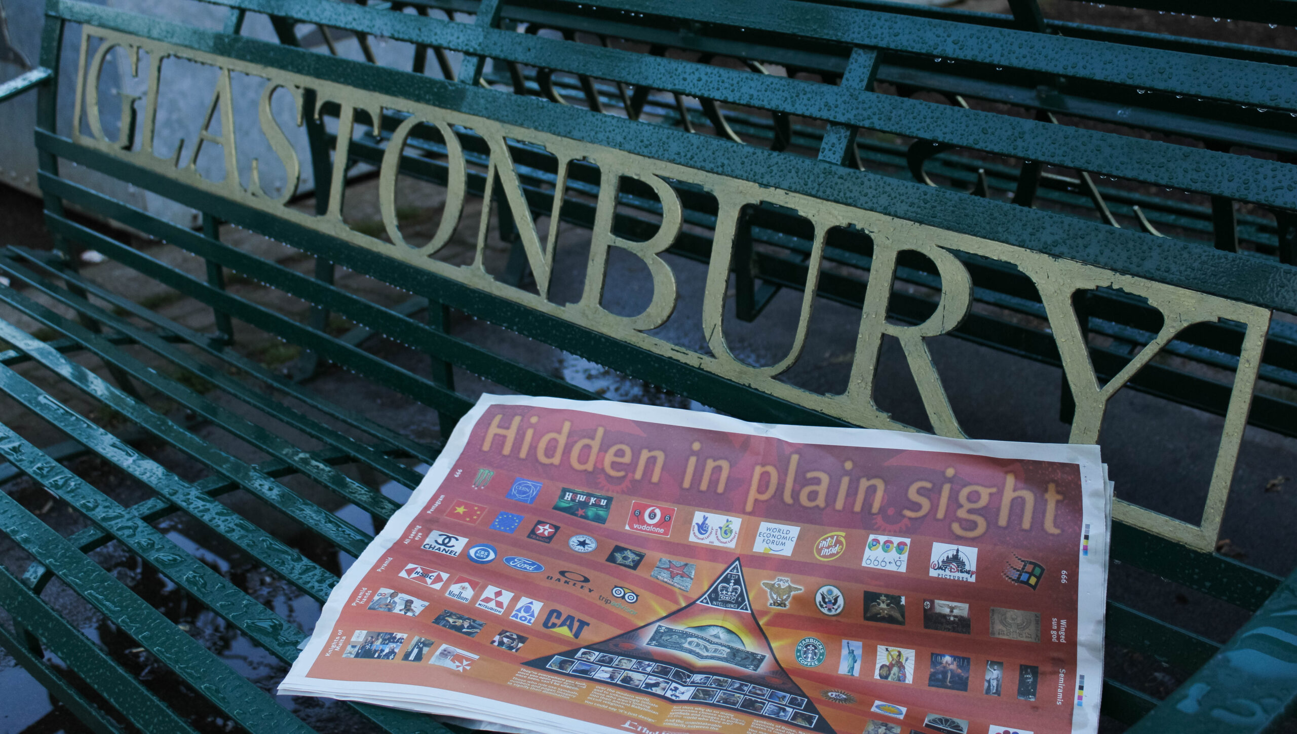 A copy of conspiracy theory "truthpaper" The Light on a green bench that has 'Glastonbury' written on it 