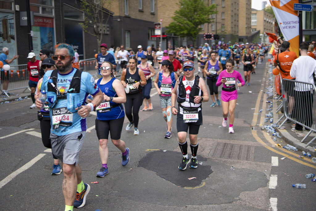 Marathon runners in running gear run through a street in London