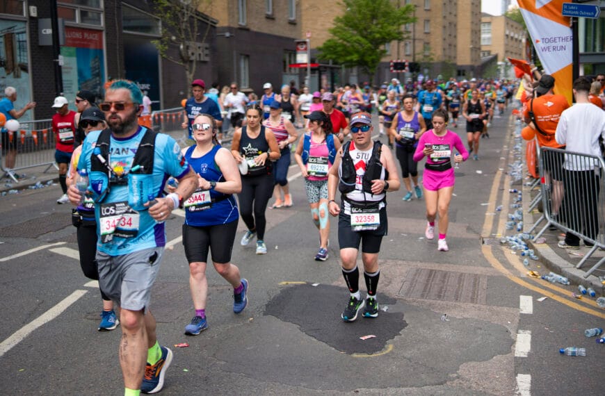 Marathon runners in running gear run through a street in London