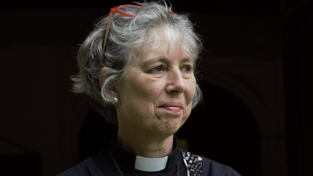 A portrait of a woman in black vlothes wearing a priest's collar