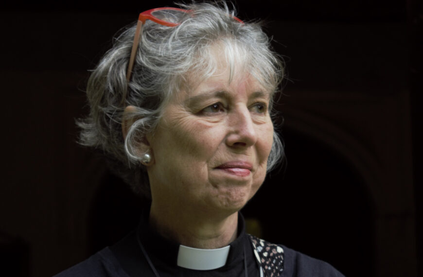 A portrait of a woman in black vlothes wearing a priest's collar