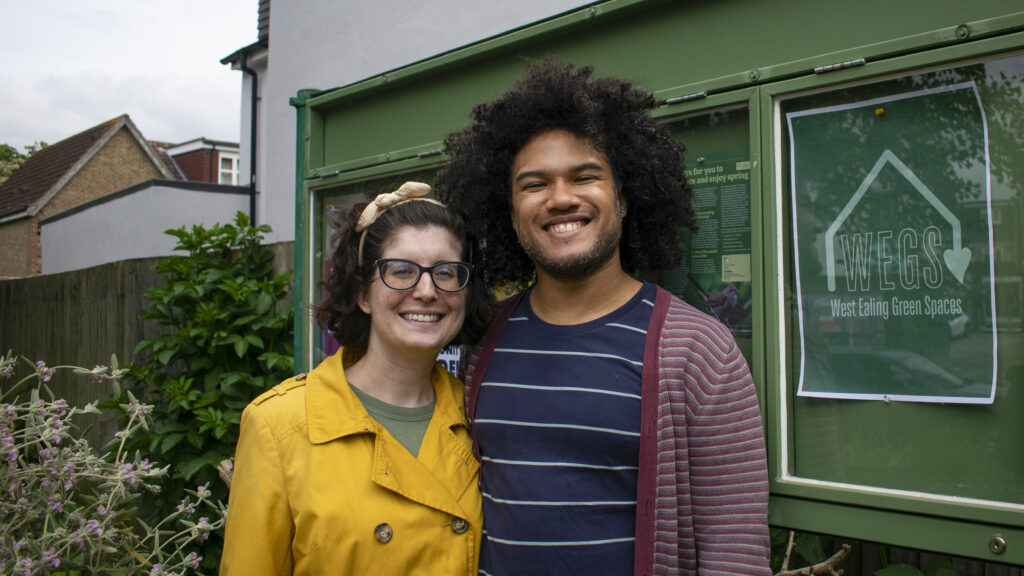 A man and a woman smiling in a community garden