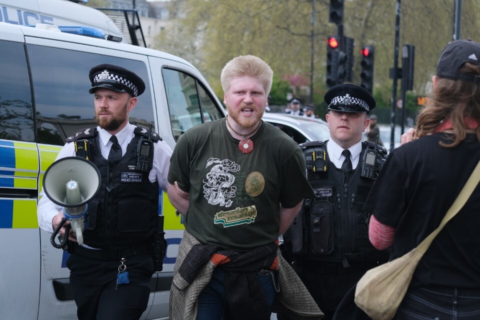 A young activist is arrested by two police officers in London