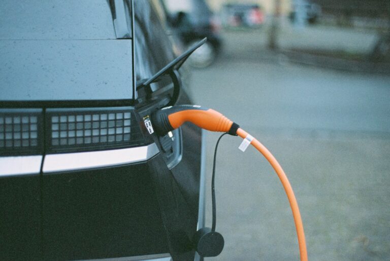 A black electric car charges with an orange cable